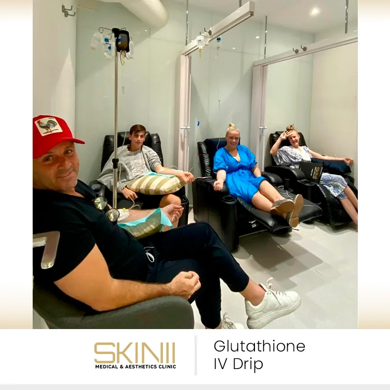 Clients at Skin111 Clinic relaxing in recliner chairs while receiving intravenous glutathione IV drip therapy in a modern treatment room.